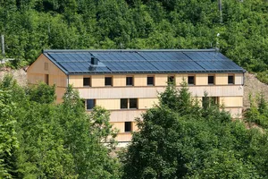 Langgezogener Holzbau umgeben von Nadelwald