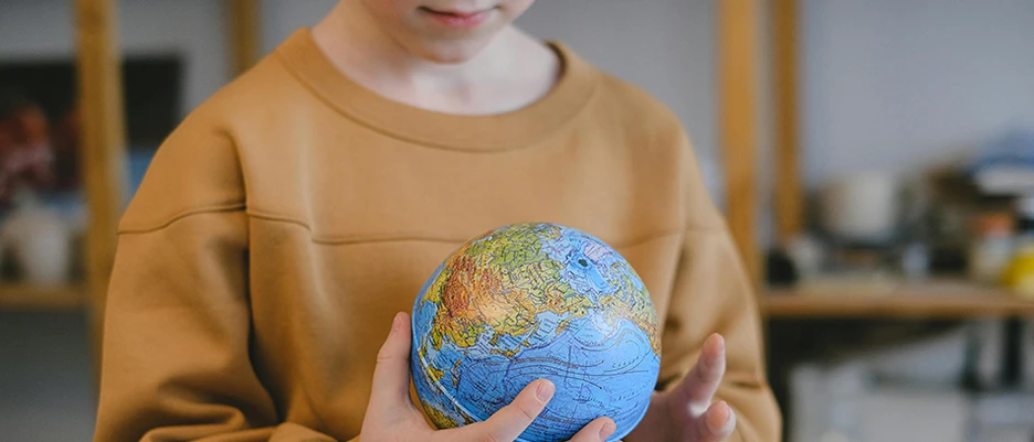 Ein Testament für die Zukunft. Symbolfoto mit einem Kind, das einen Globus in der Hand hält. Das Bild steht für die Möglichkeit mit dem eigenen Testament die Zukunft zu gestalten.