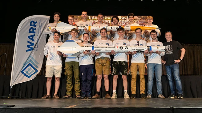 Studierende des WESP-Teams steht in zwei Reihen hintereinander und präsentieren zwei selbstentwickelte Raketen 
