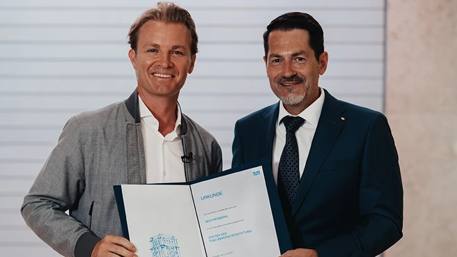 zwei Männer bei einer Urkundenübergabe schauen freundlich in die Kamera. Links der Rennfahrer Nico Rosberg, der neuer Stifter der TUM Universitätsstiftung geworden ist, rechts TUM-Präsident Prof. Thomas F. Hofmann. 