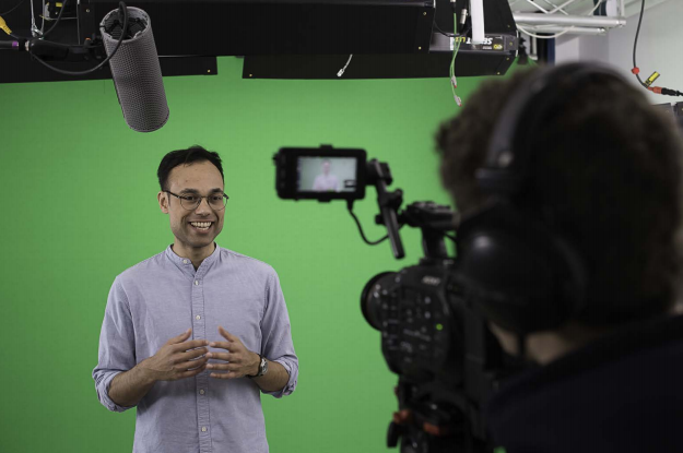 A young man standing in front of a video camera.